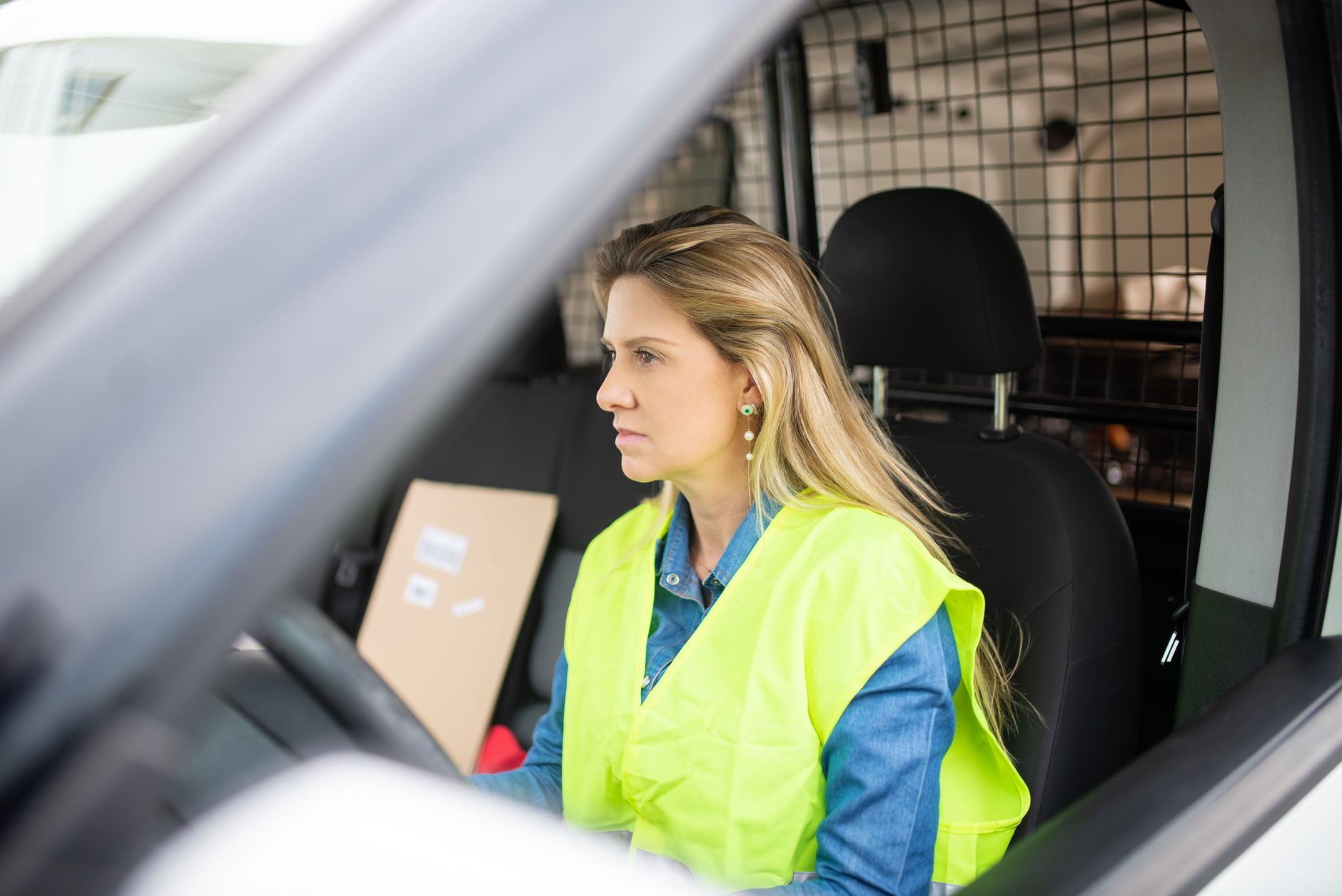 An ordinary delivery driver climbing into a parked unbranded van at a UK contractor outbase, Bracknell setting, early…