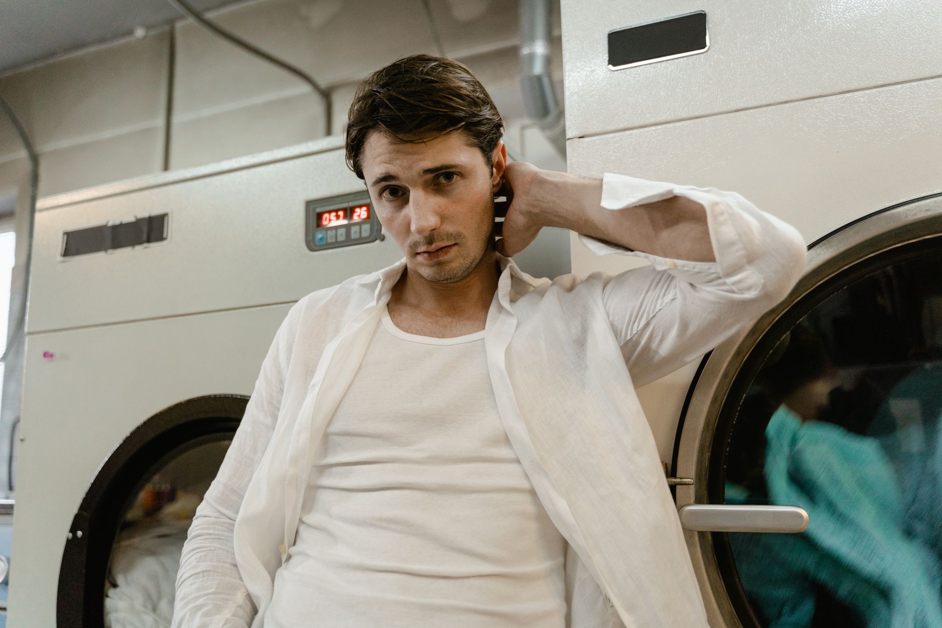 In a compact UK utility room, a professional two-person crew positioning a large tumble dryer in its agreed space, both…