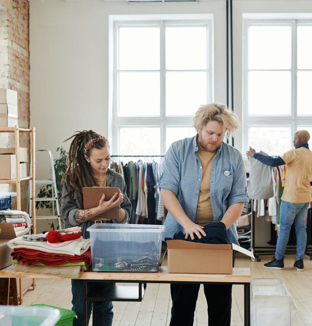 In a modest UK kitchen, two delivery and installation crew members carefully removing protective packaging from a…