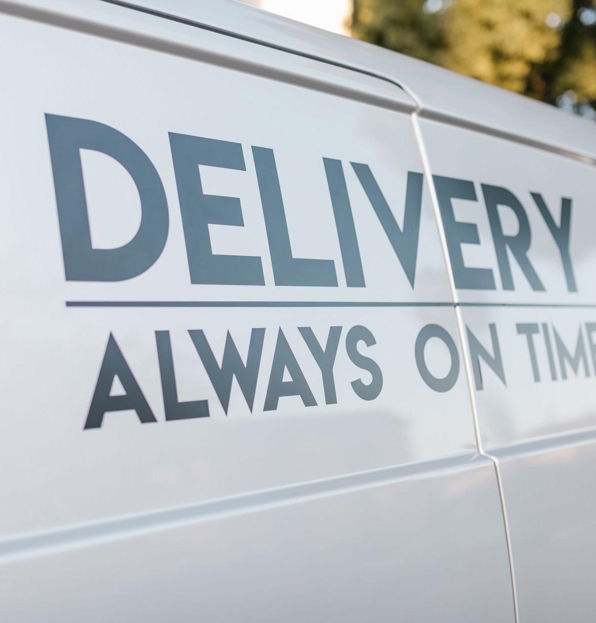 Self-employed delivery drivers reviewing a delivery schedule with a Parcelink branded van nearby