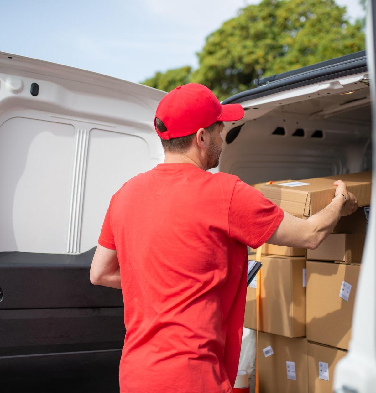 Two delivery drivers in a suburban UK neighbourhood, expertly carrying a large appliance towards a house