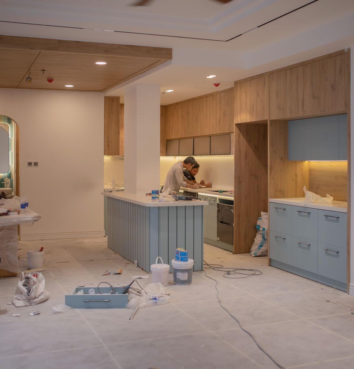 Two delivery men installing a washing machine in a kitchen