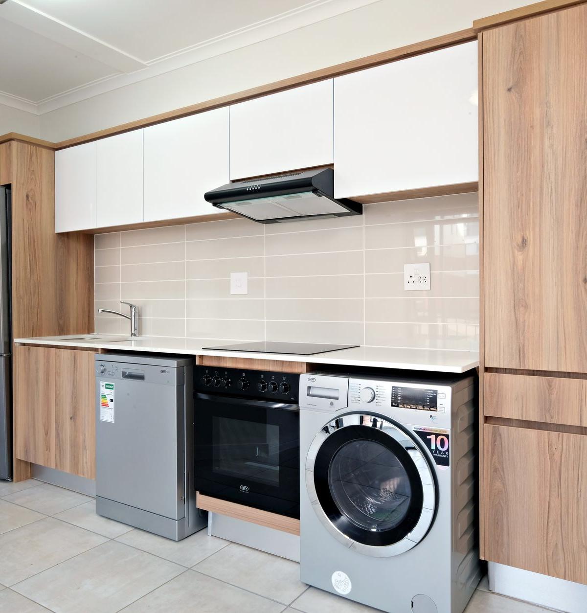 Professional delivery team installing a washing machine in a kitchen