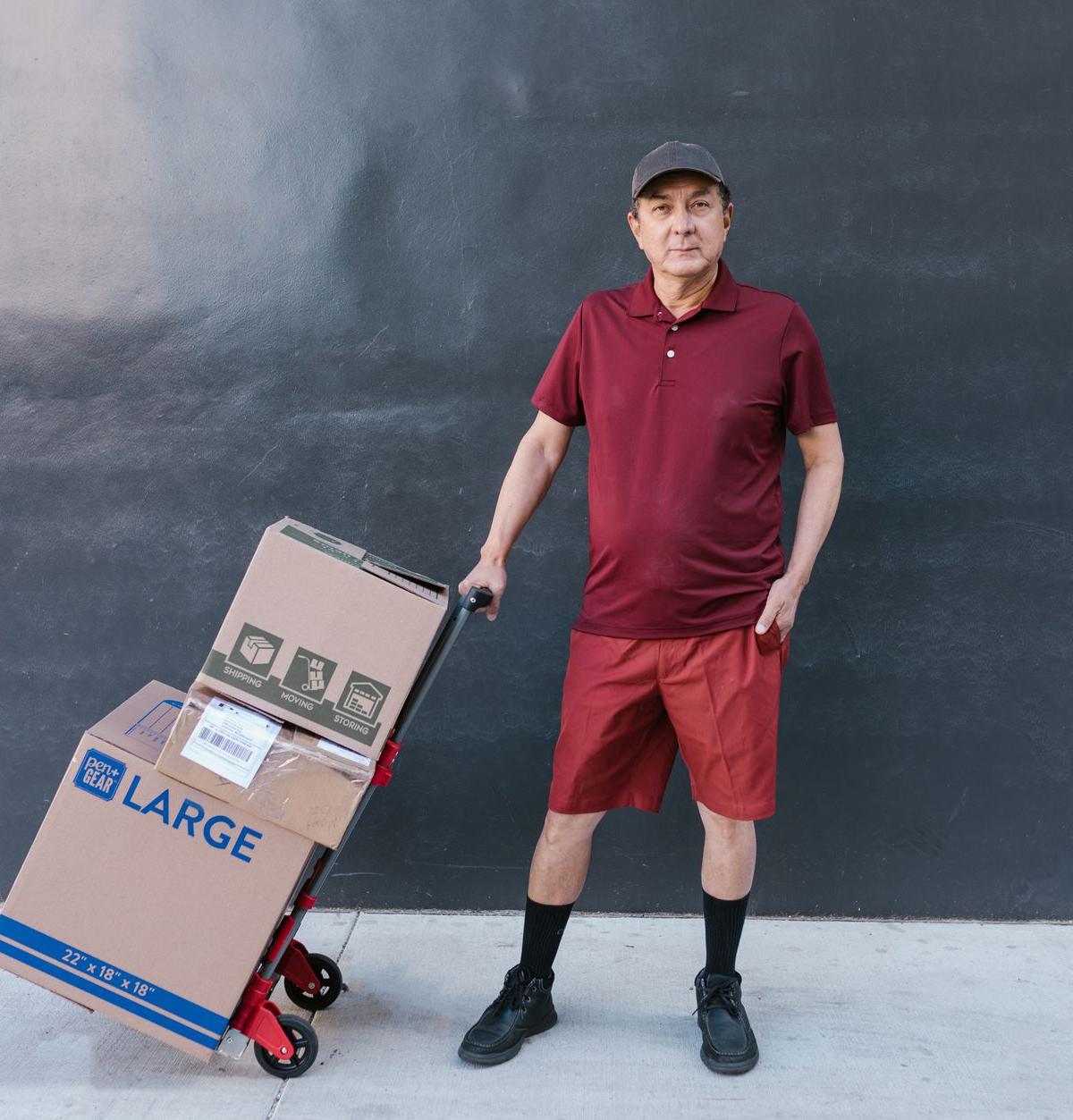 Outside a British terraced house: two ordinary delivery crew members guiding a boxed refrigerator on an appliance trolley…