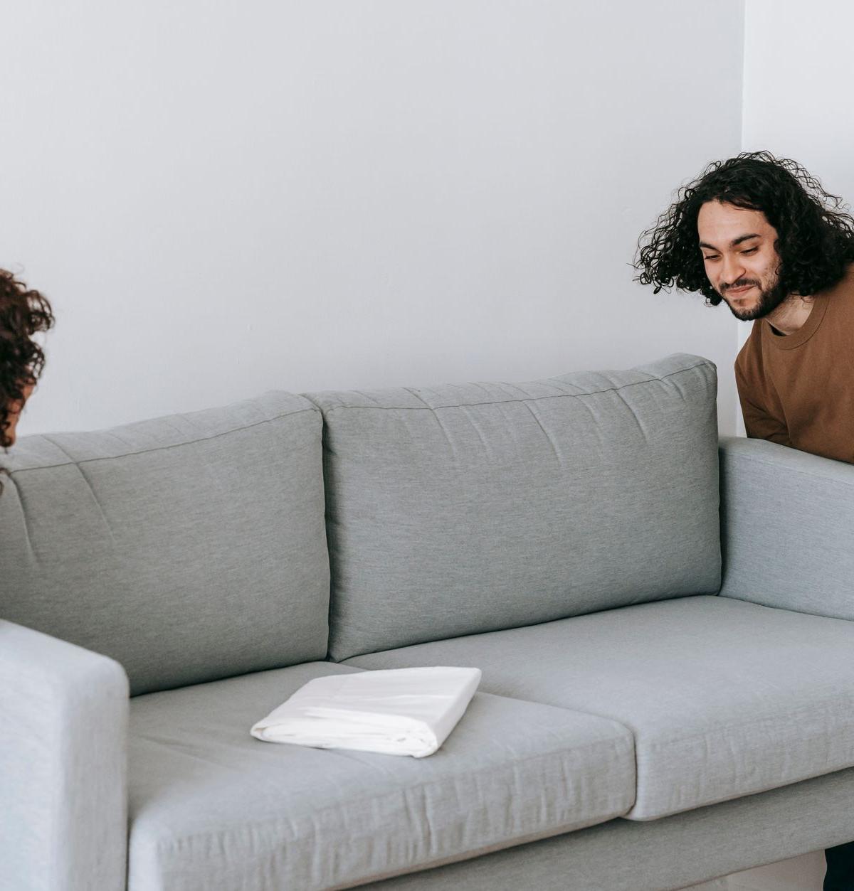 Self-employed drivers carrying a sofa into a living room
