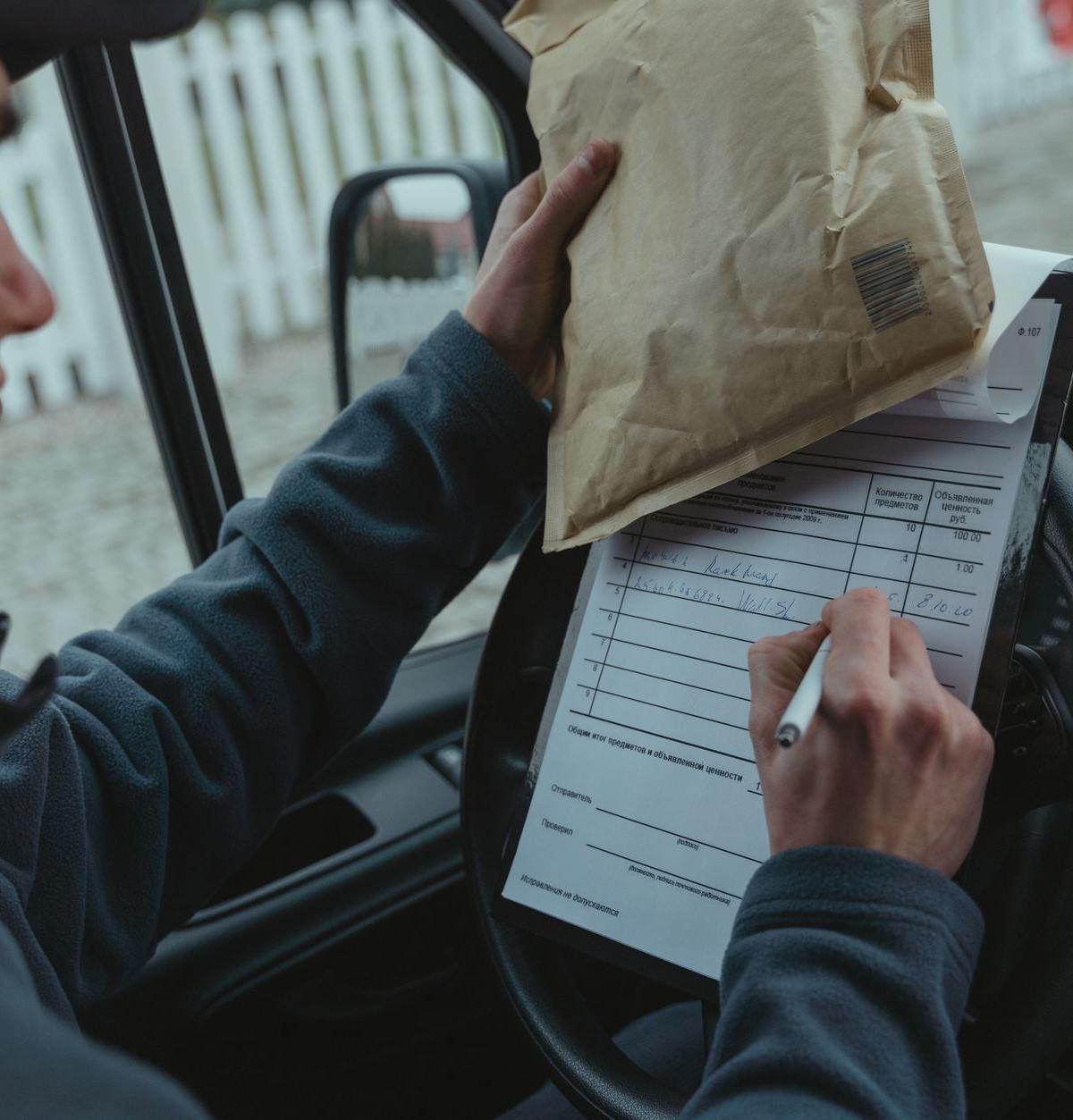 Self-employed driver checking delivery paperwork in van