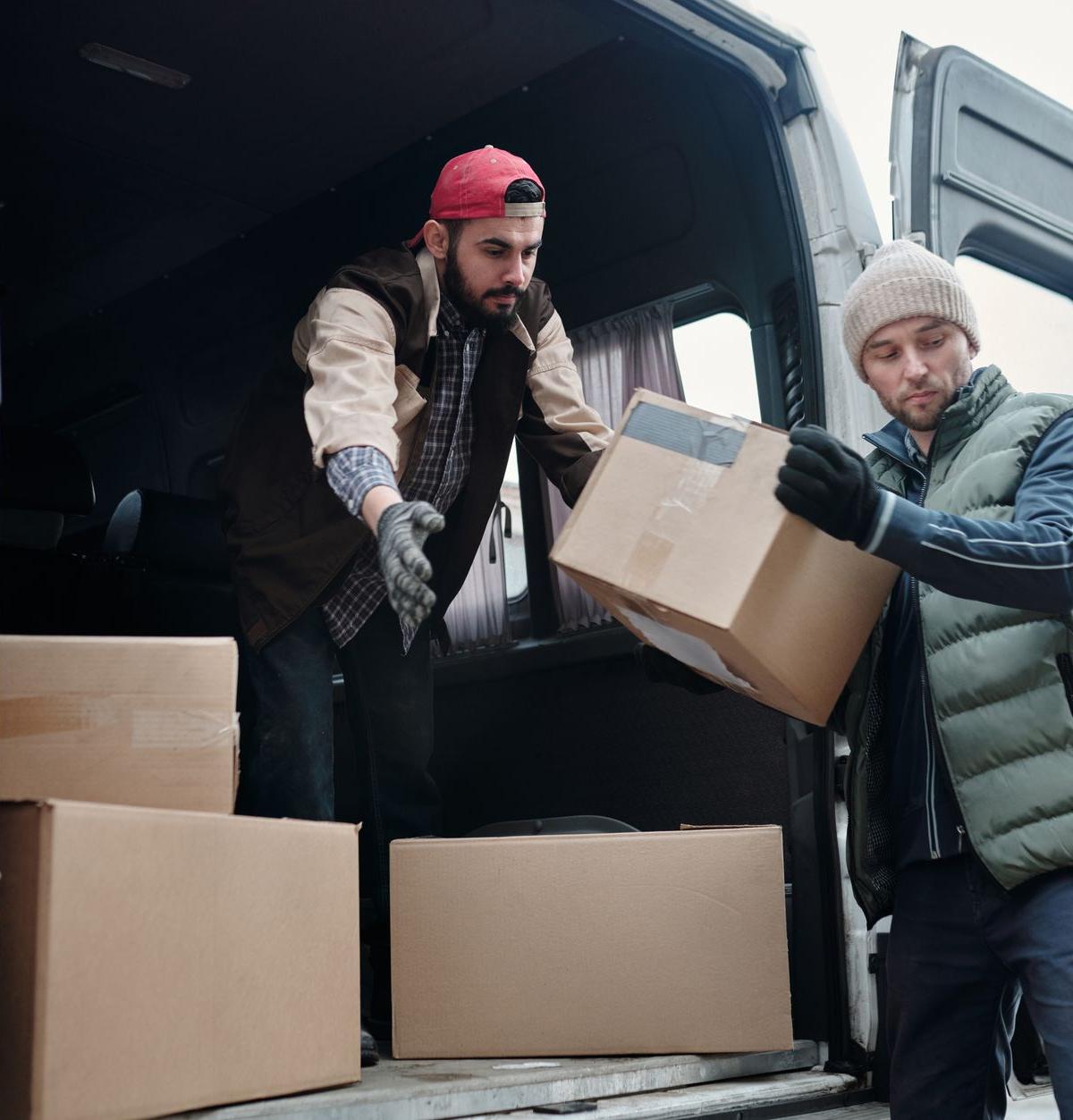 Two delivery crew members unloading a washing machine