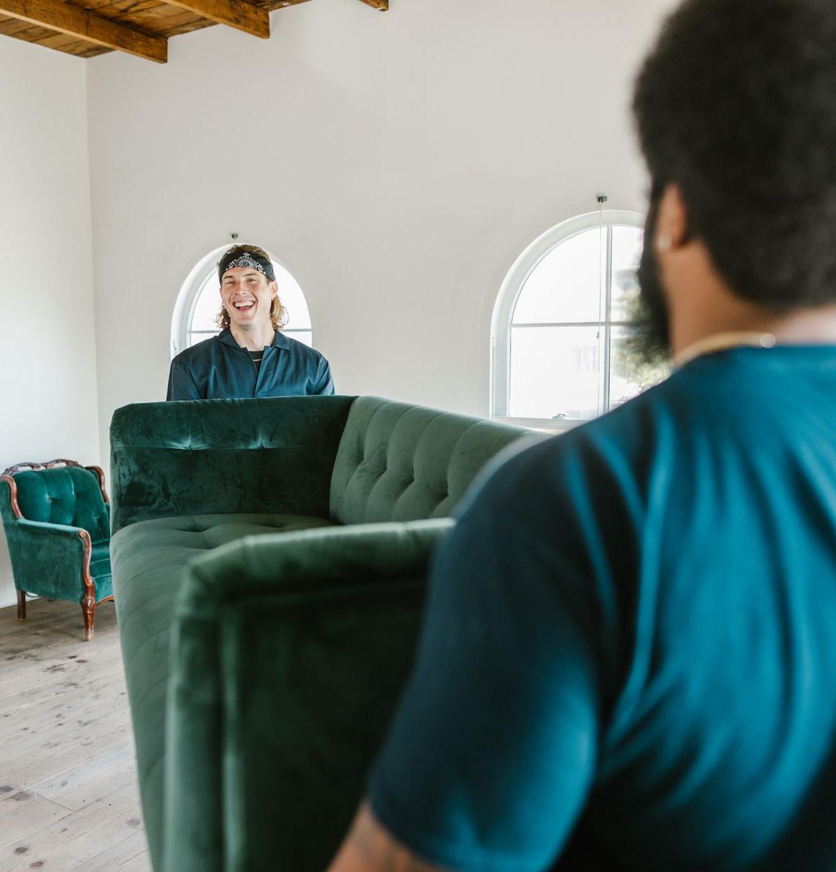 Two-person delivery crew carefully carrying a sofa into a home