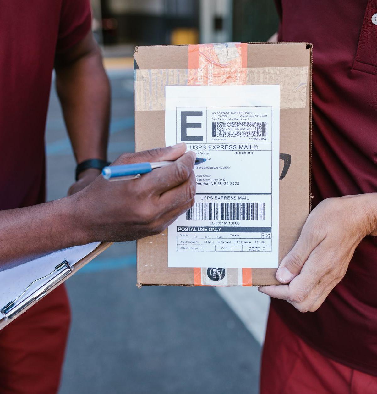 Two ordinary delivery crew members checking the load restraints inside a parked delivery van at a UK industrial estate…