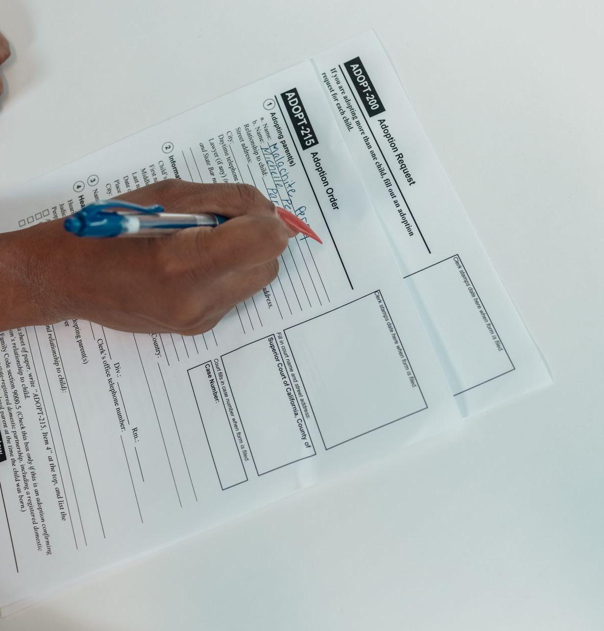 A delivery driver completing paperwork at a small dispatch counter inside a UK contractor outbase, van keys resting…